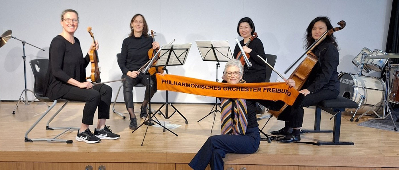 Vier Musiker des philharomischen Orchesters auf der Bühne mit ihren Streichinstrumenten, 2 Geigen, 1 Bratsche, 1 Cello